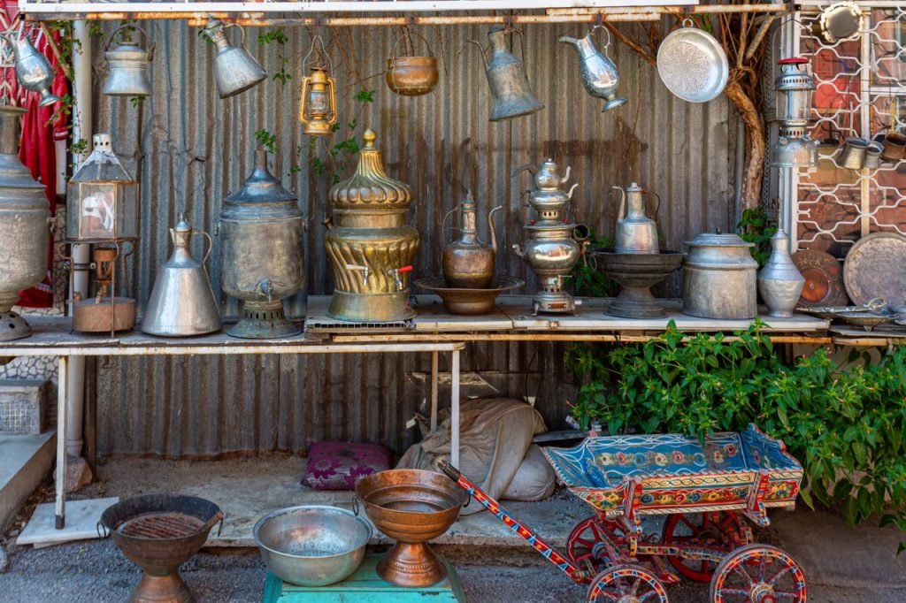 A collection of vintage metalware and lanterns displayed in an outdoor market setting.
